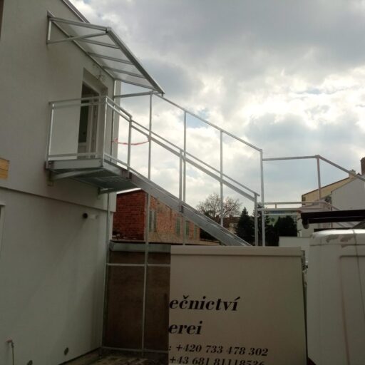 Pozinkované schodiště s podestou, zábradlím a konstrukcí pro protipožární stěnu